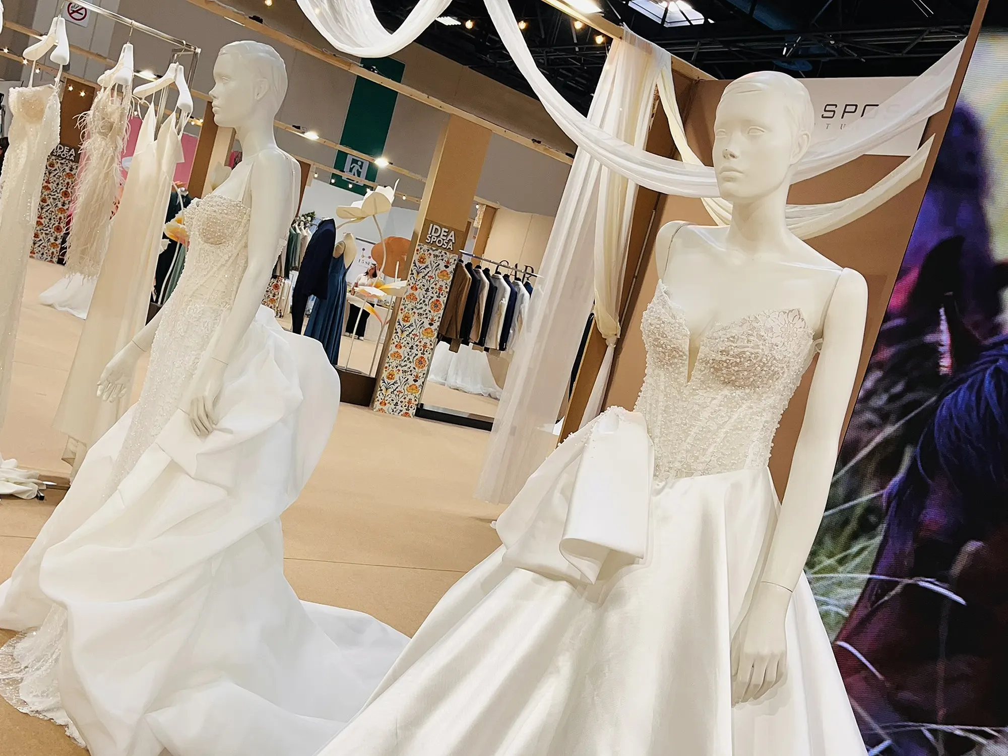 Abiti da sposa in raso e organza sui manichini di uno stand a Idea Sposa Torino